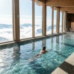 Femme nageant dans la piscine d'un spa dans les Alpes face aux sommets enneigés.