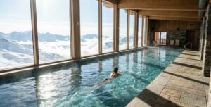 Femme nageant dans la piscine d'un spa dans les Alpes face aux sommets enneigés.