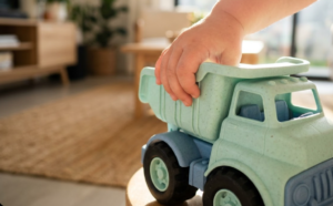Gros plan d'une main d'enfant tenant un camion en plastique recyclé à la texture mate